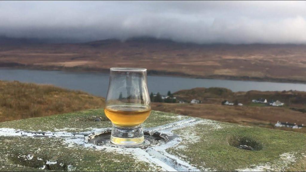 A glass of whisky with hills and sea in background