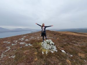 girl with arms outstretched on top of a hill