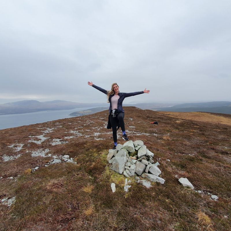 girl with arms outstretched on top of a hill