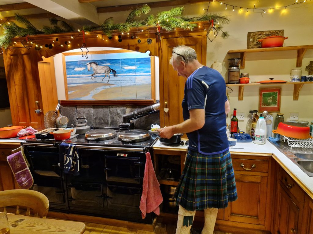 A man in a kilt by a stove