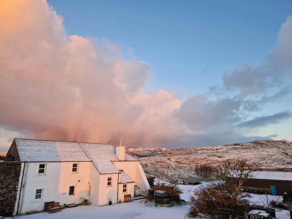 Two cottages in the snow with big clouds behind them