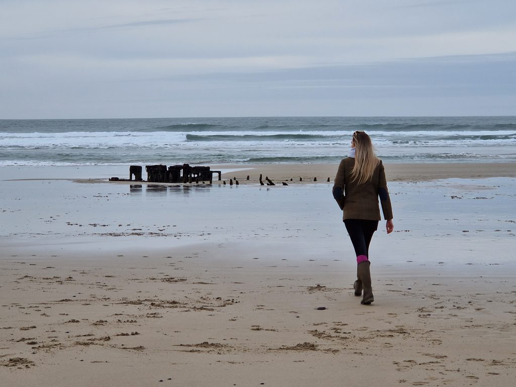 lady with long hair walking towards the sea