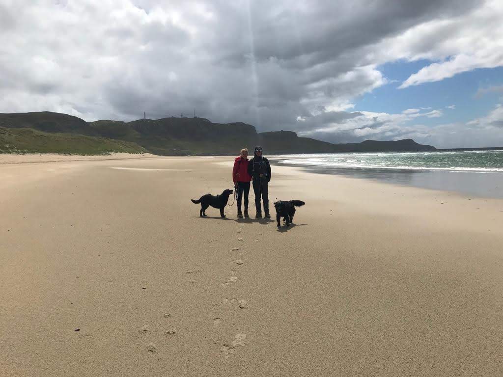 2 people on beach with 2 dogs