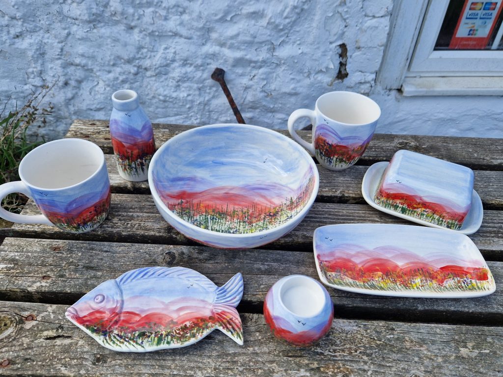 A bowl a mug, a buttery dish a fish and a tealight holder on a wooden bench