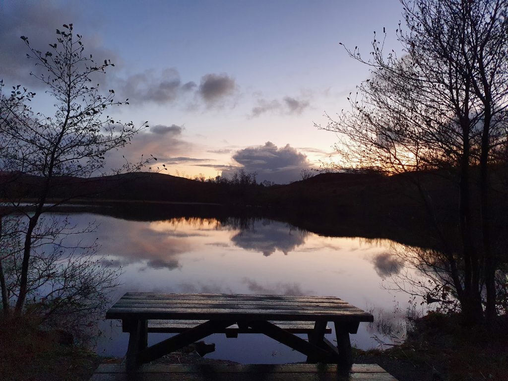 Picnic bench beside a loch at dusk