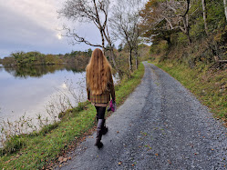 Girl walking on a track beside a loch