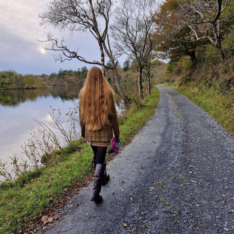 Back of girl walking along track beside a loch