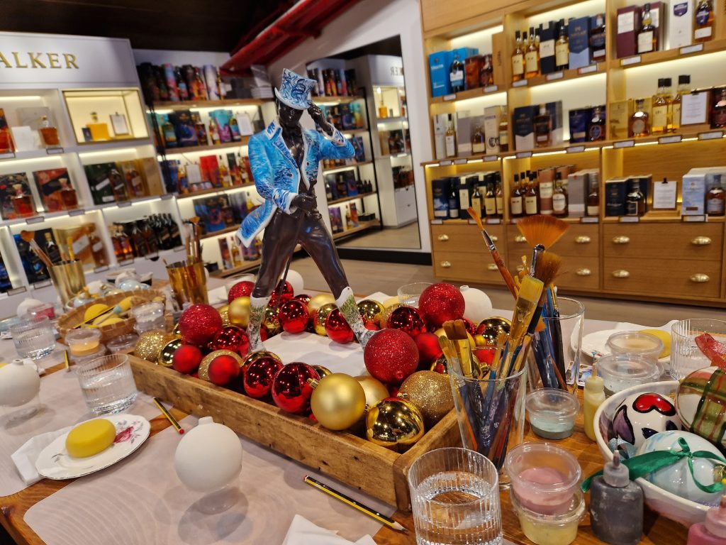 A table with a tatue of a striding man on it surrounded by baubles