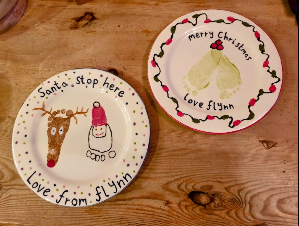 two painted plates with footprints made into santa and reindeer
