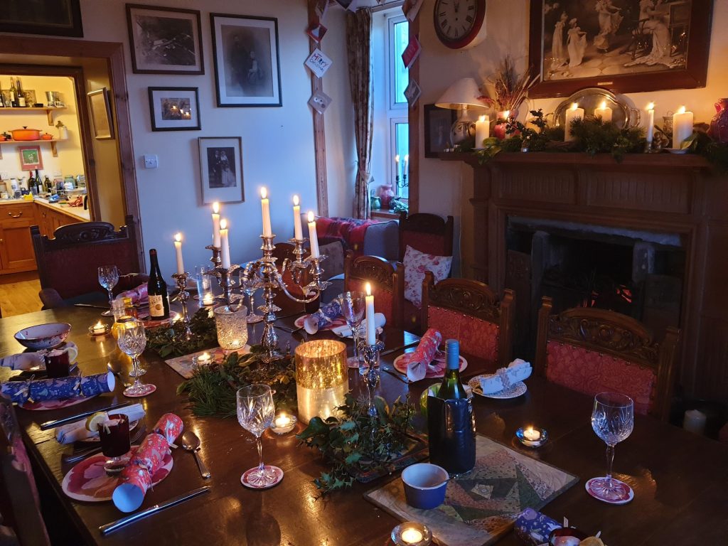 Christmas table set with candles. Fireplace with pine surround