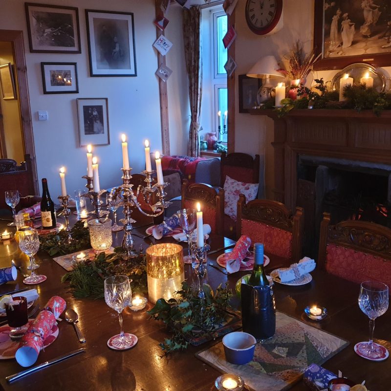 Christmas table set with candles. Fireplace with pine surround