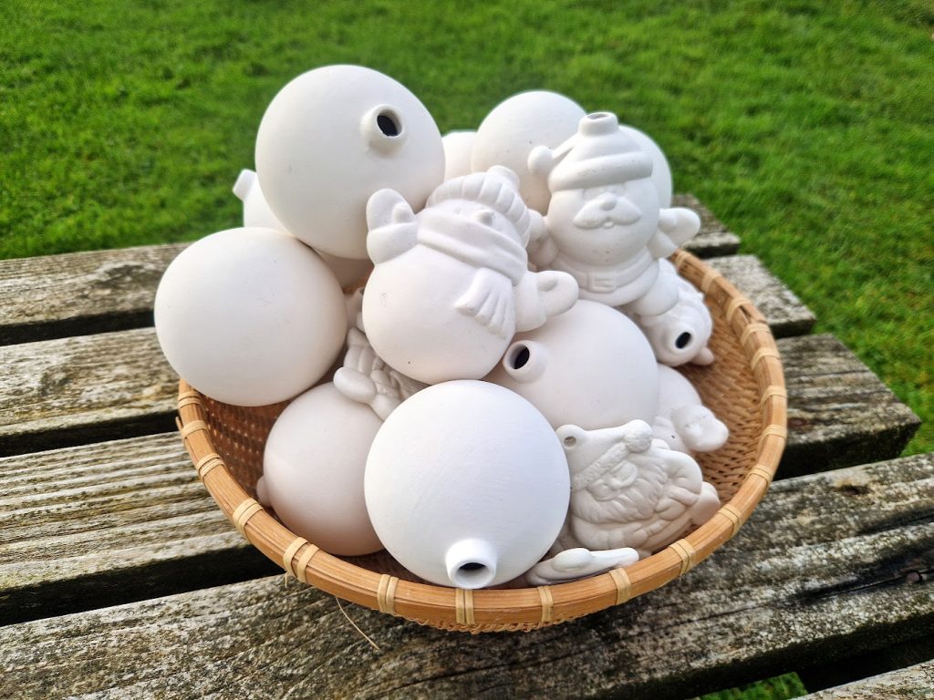 A basket filled with round baubles, and snowmen shaped baubles and santa shaped baubles
