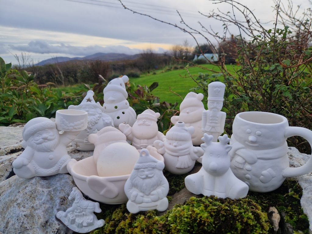 A collection of santa ornaments, reindeer, mugs and baubles on a wall.