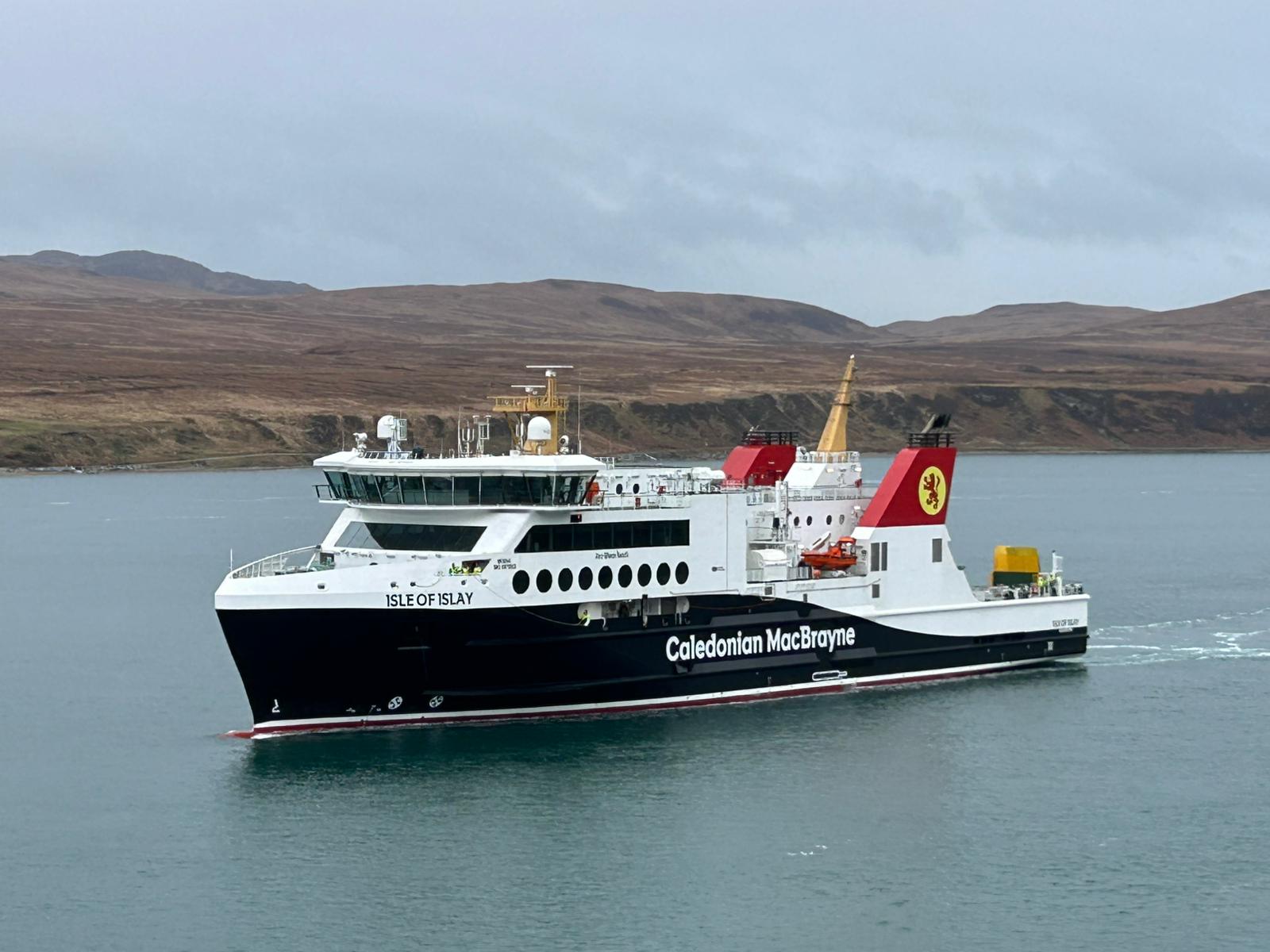 A large ferry boat on the sea with land and hills in the background