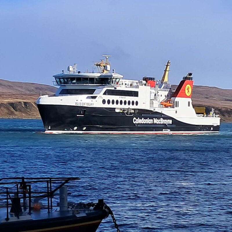 A large ferry boat on the sea with hills in the background