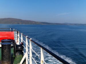 The sea with an island in the distance. A ferry deck on the foreground with railings